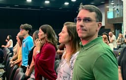 Flávio Bolsonaro ao lado da esposa, sinalizando desistência da candidatura e elogiando Tarcísio. Reprodução: Oglobo