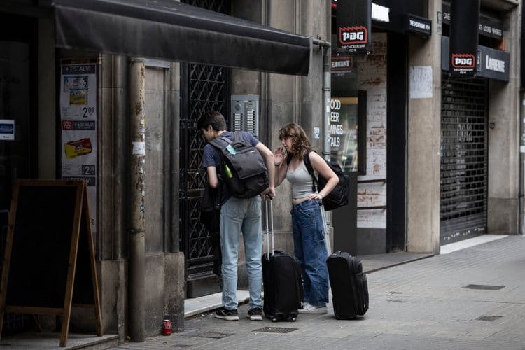 Turistas em frente a um piso turístico em Barcelona, alvo de ações contra anúncios ilegais. Reprodução: El País