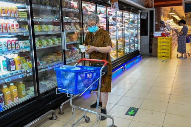 Mulher faz compras de itens congelados em Beijing, diante da desaceleração econômica chinesa. Legenda da imagem. Reprodução: Retorno do item 11
