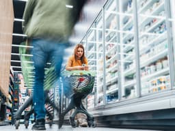 Mulher analisa ofertas e cupons enquanto faz compras no supermercado.; Legenda da imagem. Reprodução: Business Insider