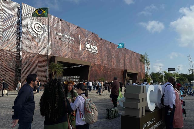 Participantes caminham em frente à entrada principal da COP30. Reprodução: Retorno do item 11