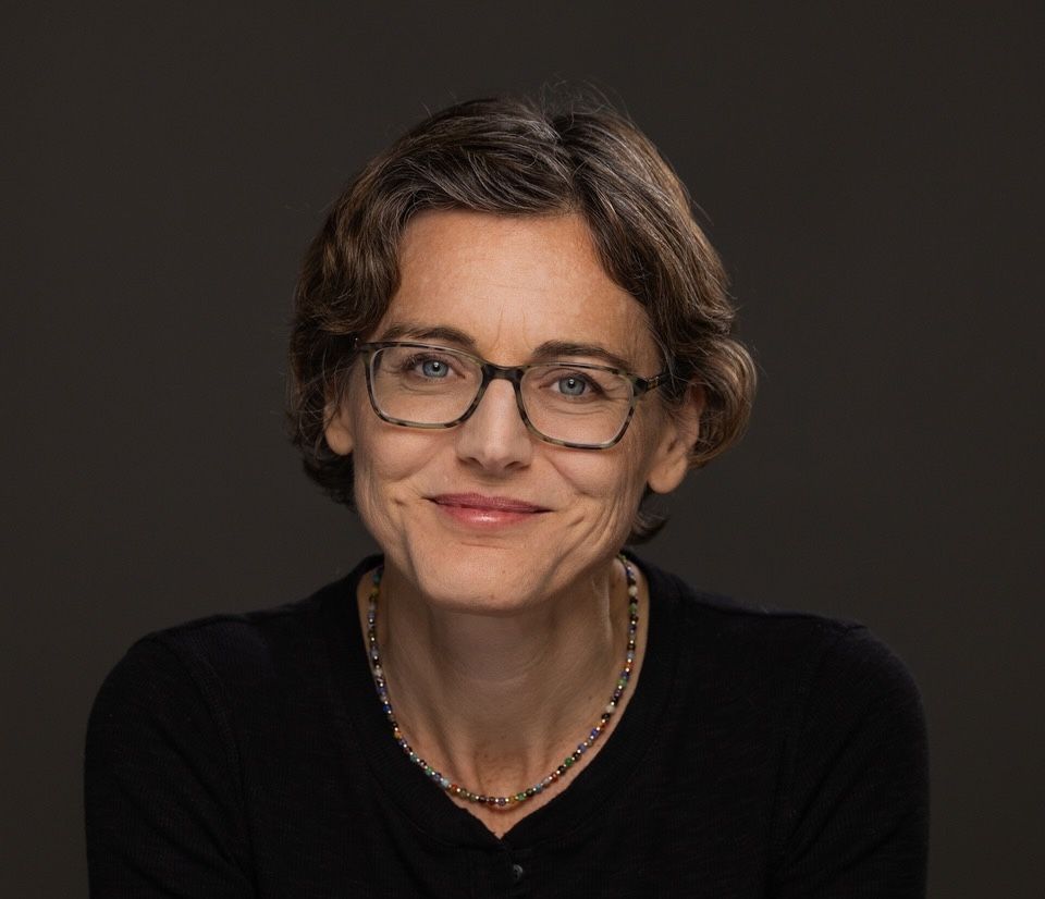 Engenheira da Red Hat sorri em retrato com fundo escuro e roupa preta.