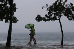 [Cariocas caminham sob chuva no Rio, com previsão de granizo.]. Reprodução: Oglobo