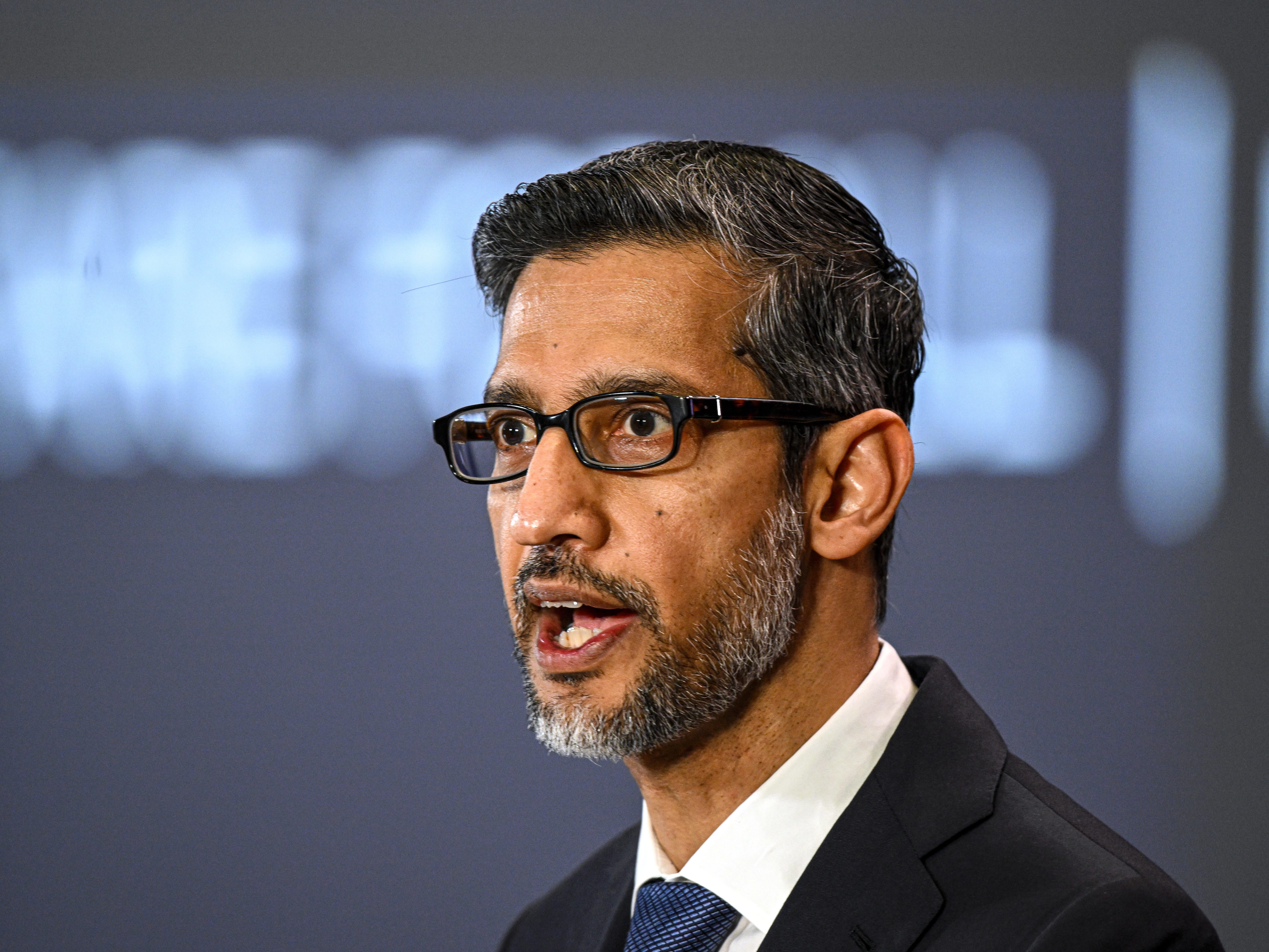 Executivo da Google fala em evento, com expressão séria e fundo desfocado.